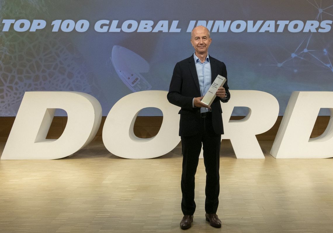Photographie d'Éric-Philippe Vinesse tenant un trophée entre ses mains. En arrière-plan, une projection vidéo indique : "TOP 100 Global Innovators 2023 ". DORD (Direction Opérationnelle Recherche & Développement)