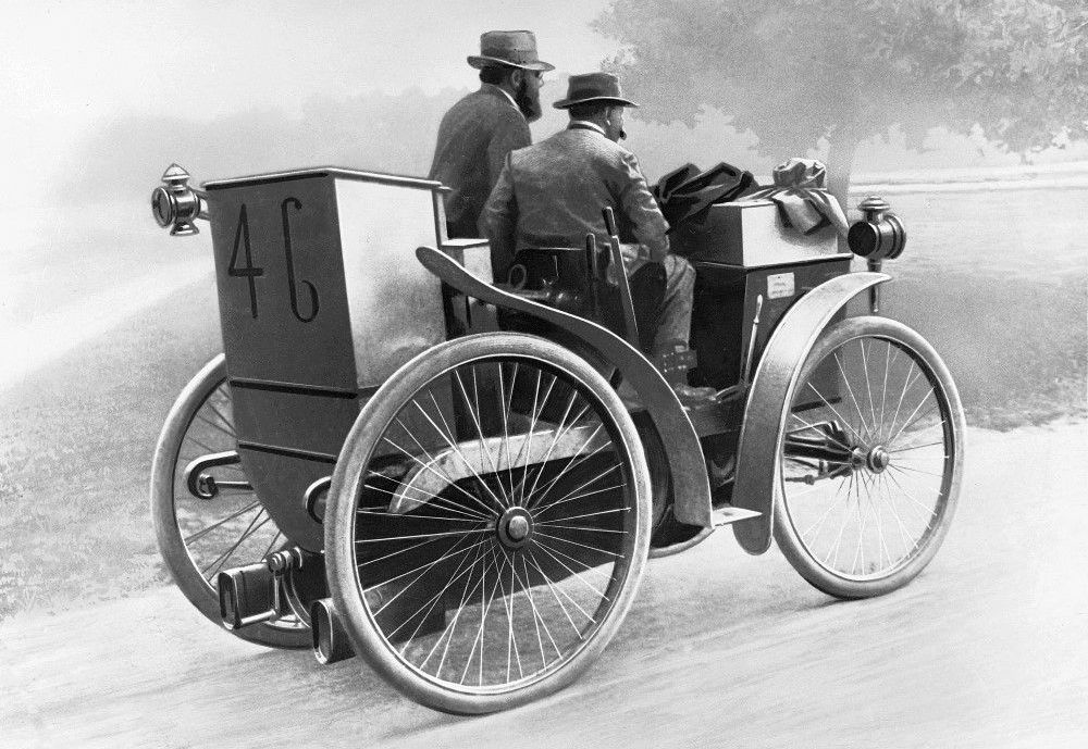 Black and white illustration showing André Michelin at the wheel of 'l'Eclair', a man is seated to his right, passenger side. The car has the number 46 on the rear.