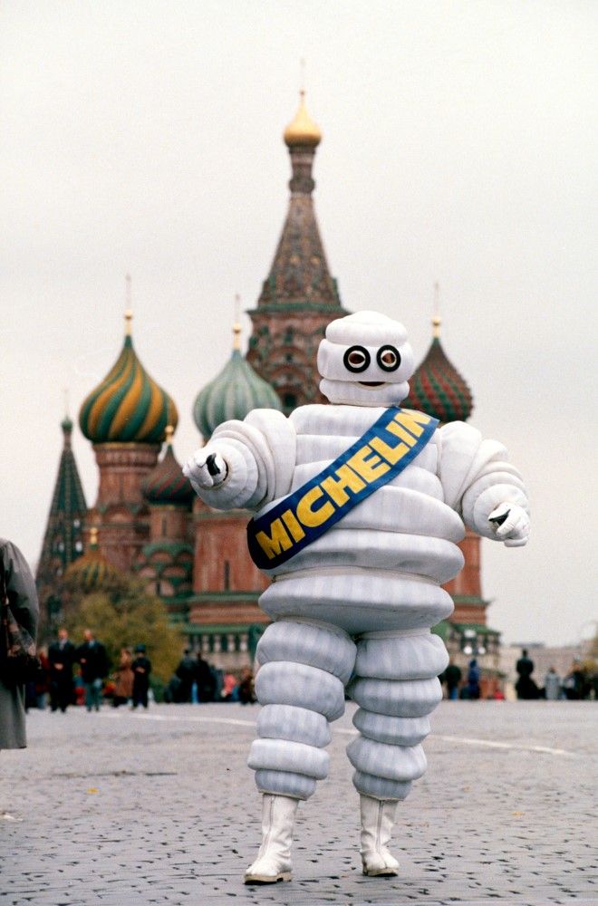 Photographie d'une mascotte du Bibendum devant la cathédrale Saint-Basile-le-Bienheureux, emblème de Moscou (Russie).