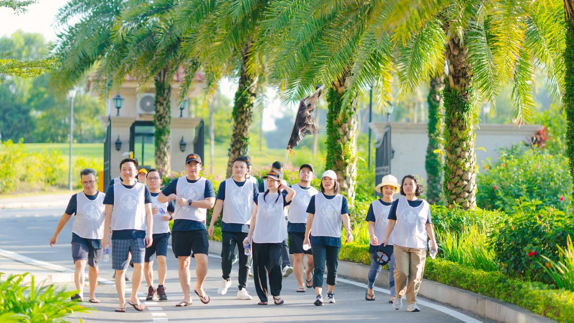 A group of Michelin Asia Pacific employees walking together along a palm-lined pathway.