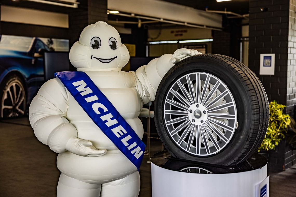 The Michelin Man standing beside a Michelin tire display, representing the brand’s iconic legacy in mobility and innovation.