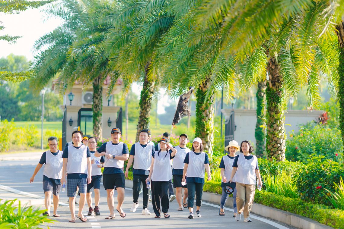 A group of Michelin Asia Pacific employees walking together along a palm-lined pathway.
