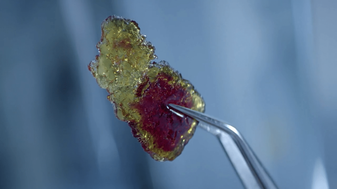 Zoom in on a crystallized ResiCare resin sample held by a clamp